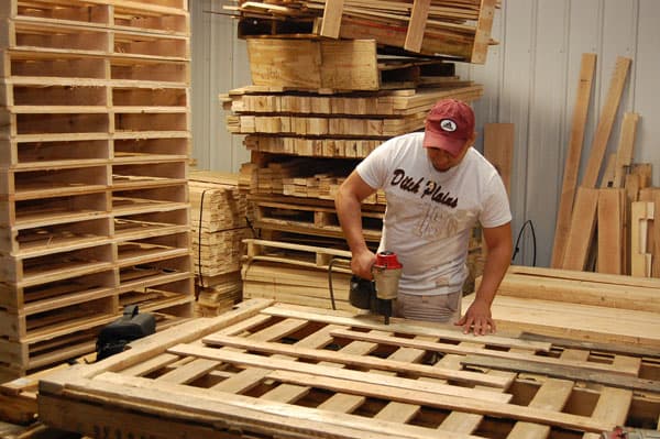A Golden Eagle Pallet working nailing down a custom Pallet with a nail gun.
